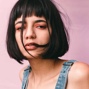 woman with short black bob against a pink background
