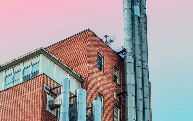 Red brick building with three ducts against a pink-blue sunset