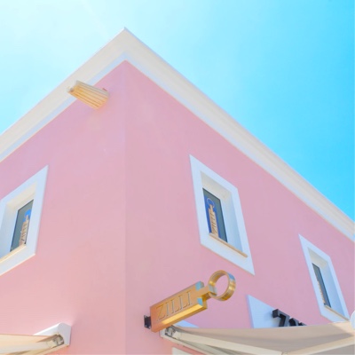 Pink house with white windows against a light blue sky